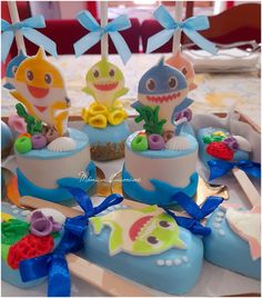 there are some little cakes on the table with blue ribbon around them and one is decorated like a shark