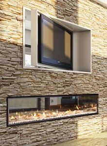 a television mounted to the side of a stone wall next to a fire place in a living room