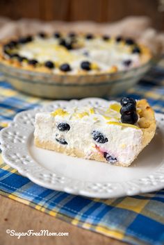 a slice of pie on a plate with blueberries and lemons in the background