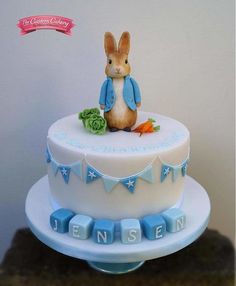 a white cake with blue icing and a rabbit on top