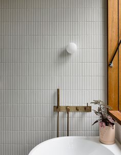 a white bath tub sitting next to a wooden window sill with a plant in it