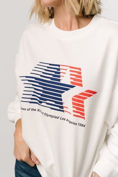 Throw it back to the '84 Olympics Neutral off-white color Blue and red star logo and "Games of the XXIIIrd Olympiad Los Angeles 1984" printed across front Crew neckline Ribbing at neckline, sleeve cuffs, and hem Comfortable oversized fit Self: 60% Cotton, 40% Polyester Contrast: 95% Cotton, 5% Spandex Trina is 5'6, cup size 32D, size 2 and is wearing size XS Red Star Logo, Throw It Back, Star Logo, Red Star, Vintage Inspired Design, Off White Color, Cup Size, Crew Neckline, White Color