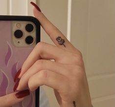 a woman holding up her phone with a small tattoo on it's left hand