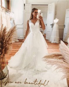 a woman in a wedding dress is taking a selfie with her phone and flowers