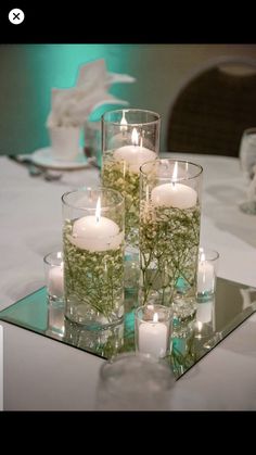 candles are placed in glass vases on a table