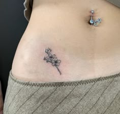 a woman's stomach with a small flower tattoo on her left side ribcage