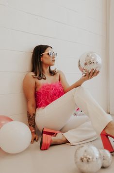 a woman sitting on the floor holding a disco ball