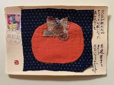 a piece of fabric with an orange on it and japanese characters written in the background