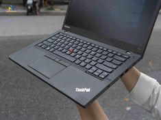 a person holding up a laptop computer in their hand with the word thinkpad on it