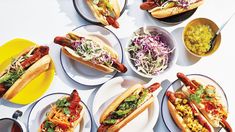 many hot dogs and condiments are arranged on plates