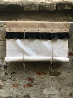 a curtain hanging on the side of a stone wall with black ruffles and rope