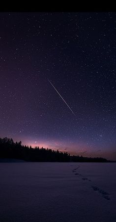 the night sky is filled with stars, and there are footprints in the snow below