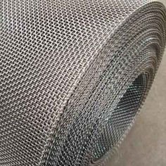 a roll of stainless steel wire mesh on the ground with grey carpeting behind it