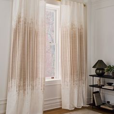 the curtains are hanging in front of a window with white drapes on it and a black lamp next to them