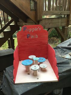 a red chair with blue plastic cups on it and a sign that says poppie's pitch