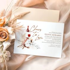 a wine bottle and flowers are on the table next to an envelope with wedding cards