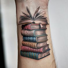 a man's arm with a stack of books tattooed on the side of it