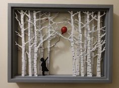 the shadow of a person holding a red balloon in front of a forest with white trees