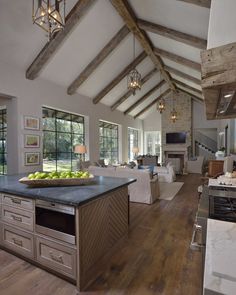 a large open concept kitchen and living room with wood flooring, exposed beams and vaulted ceiling