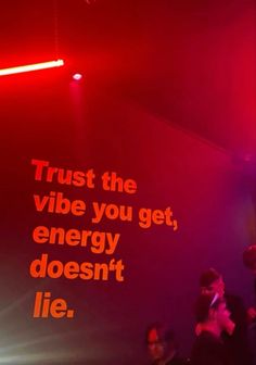 people standing in front of a red wall with words on it that say trust the vibe you get, energy doesn't lie