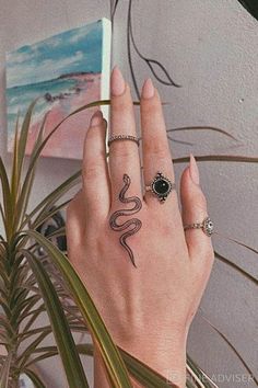 a woman's hand with tattoos on it and a plant in front of her