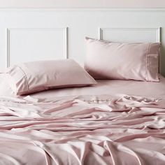 a bed with pink sheets and pillows on it