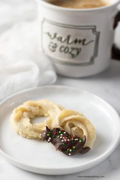 two cookies on a plate next to a cup of coffee