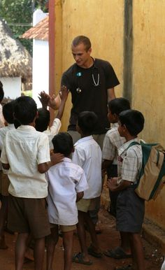 a man standing in front of a group of young boys with their hands up to each other