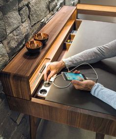 a person is using their cell phone on a table with an ipod and charger plugged into it