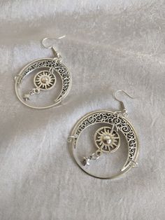 These gorgeous drop earrings feature filigree moons, suns, and star charms enclosed in a celestial circle. Perfect piece for a little everyday magic! Choose between silver or bronze Celestial Sun Design Round Jewelry, Celestial Style Silver Metal Jewelry, Silver Moon Charm Jewelry In Alloy, Celestial Silver Pierced Jewelry, Silver Moon Bohemian Jewelry, Silver Alloy Jewelry With Moon Charm, Celestial Moon Charm Earrings For Festivals, Silver Celestial Jewelry With Sun And Moon Design, Celestial Star Jewelry For Festival