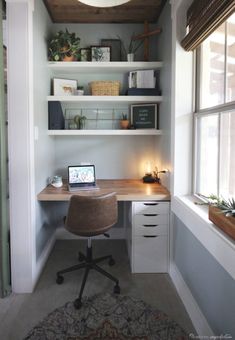 a desk with a laptop computer on top of it next to a window in a room