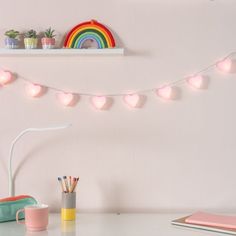 a white desk topped with a laptop computer next to a rainbow wall mounted above it