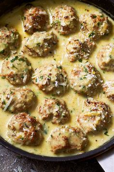 a skillet filled with meatballs and gravy on top of a table