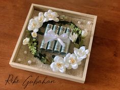 a wooden box with flowers and perfume bottles in it on top of a wood table