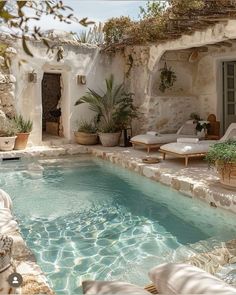 an outdoor swimming pool with chaise lounges and potted plants on the side