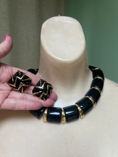 I love the bold look of black jewelry whether combined with gold or silver accents.   I matched the Napier big link necklace with a pair of unsiged clip earrings for what I think is a great look for evening or for a professional lady who is serious about looking serious at her work place. Necklace measures just over 16" and will sit right on the collar bones.  Each larger black link is (I think) lucite.  These are solid, not hollow, and domed and about 1" each.  Between each black piece is a goldplate metal 'claw'.   The neck piece will rest comfortably on the neckline.  Bold but not heavy or stiff. Snap box clasp on necklace with Napier name underneath. The earrings are clip backs.   Domeed squares with heavy black enamel and goldplate zig zag lines.   No name on these.  Just over 1" diam Black Clip-on Jewelry For Formal Occasions, Gold Jewelry Set, Black Gold Jewelry, Gold Jewelry Sets, Work Place, Box Clasp, Neck Piece, Black Jewelry, Necklace Black