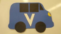 a paper cut out of a blue bus with the letter v on it's side