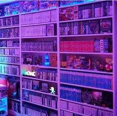 a room filled with lots of books and video game consoles on shelves next to each other