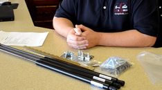 a man sitting at a table with his arms crossed and fishing rods in front of him