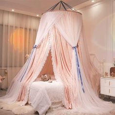 a pink canopy bed with white sheets and blue ribbon on the top, in a girls'bedroom