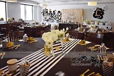 a black and white striped table cloth with flowers in a vase on it at a party