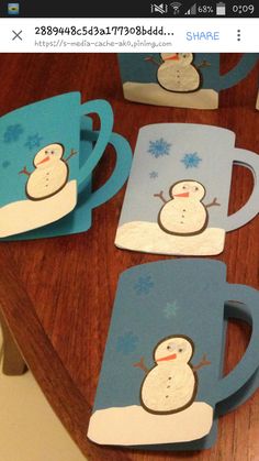 four snowman mugs sitting on top of a wooden table next to each other