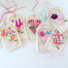 four handmade tags with hearts and flowers on them hanging from twine string together