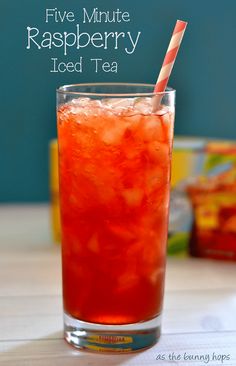 a tall glass filled with ice tea sitting on top of a table