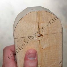 a hand holding a piece of wood with holes in it