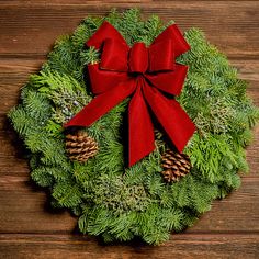 Christmas wreath made of fir, cedar, and juniper with pine cones and a red with gold back bow on a wood background. Pottery Barn Cedar Wreath, Christmas Wicker Wreath, Christmas Wreath With Bow Red, Boxwood Wreath Red Ribbon, Christmas Wreaths With Redbirds, Outdoor Christmas Window Wreaths 20", Led Garland, Dried Floral Wreaths, Gold Hangers