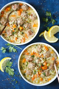 two bowls of soup with meat, carrots and parsley next to lemon wedges