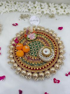 an intricately decorated plate with fruit and flowers on it, surrounded by petals in the background