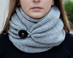 a woman wearing a gray scarf with a black button on it