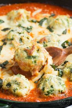 broccoli and cheese covered meatballs in a skillet with a wooden spoon